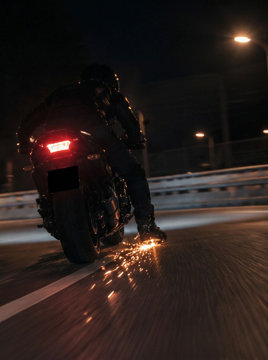 Rider's boot at night as the Foot Spark element meets the road surface, sparks spraying from the contact point