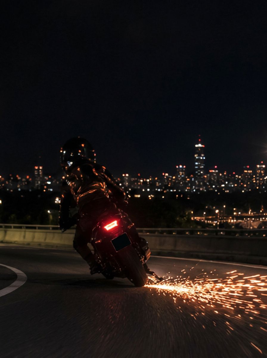 Motorcyclist leaning into a night corner as bright orange sparks stream from under the rider's boot